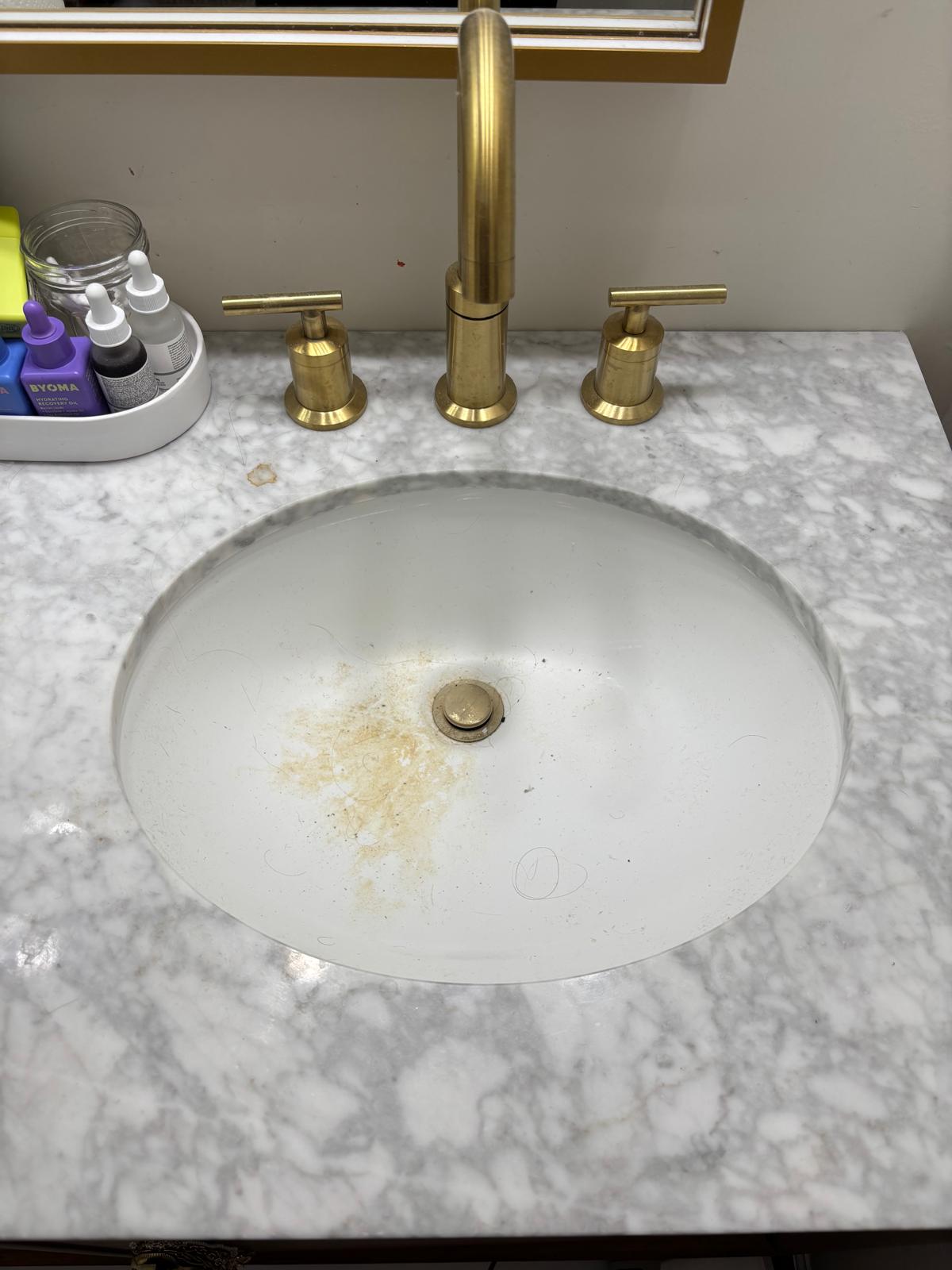 Bathroom sink and marble vanity with visible residue before cleaning