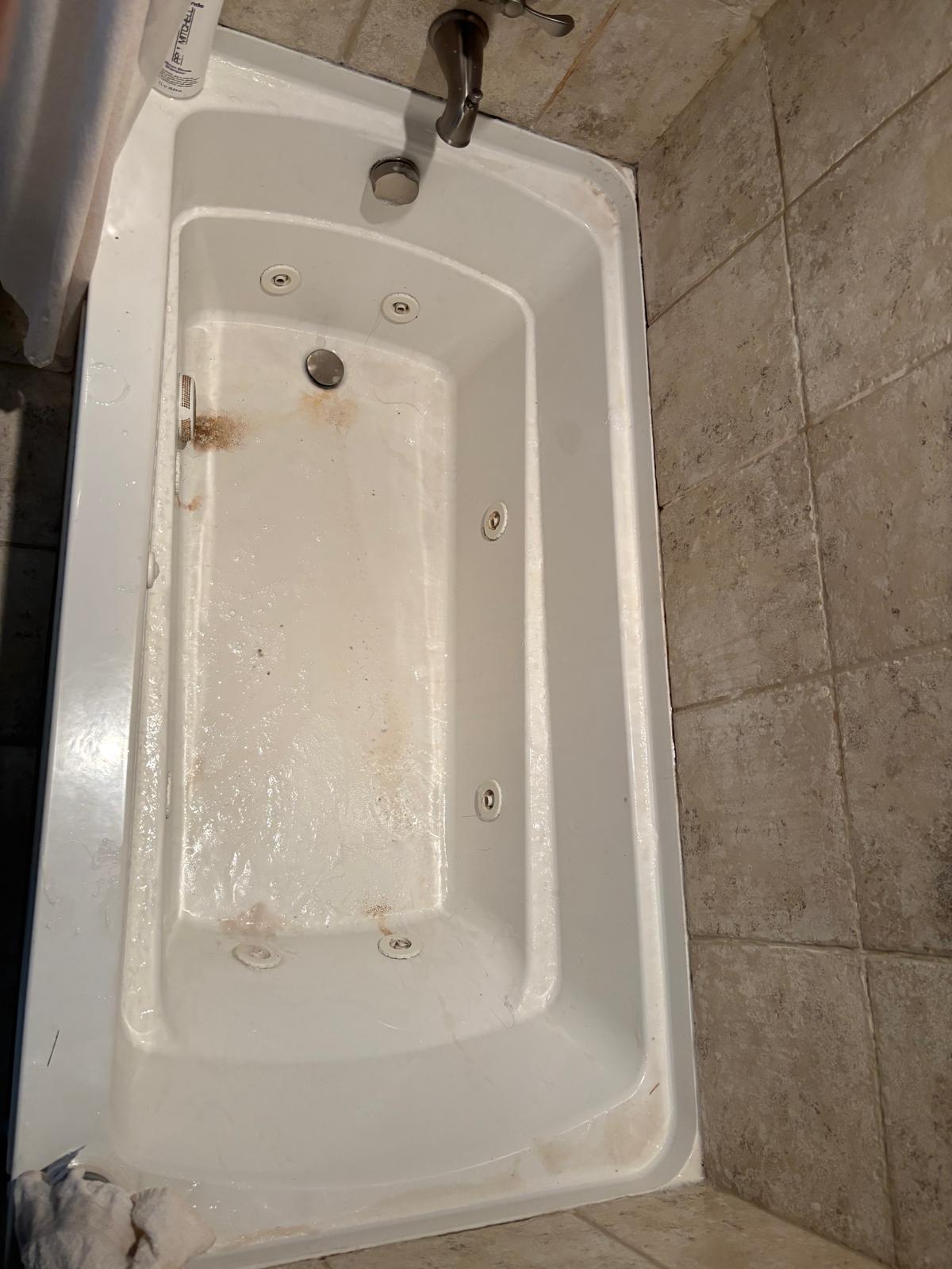 Jetted bathtub with visible residue before cleaning